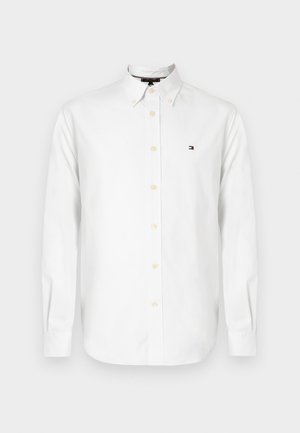 Bijela košulja s dugim rukavima na kopčanje, s okovratnikom na kopče i malim izvezenim logotipom na lijevoj prsnoj strani.