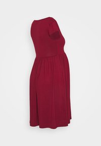 Vestido curto burdeos de mangas curtas, com decote redondo, corpete justo e saia franzida. Feito de um tecido suave e elástico.