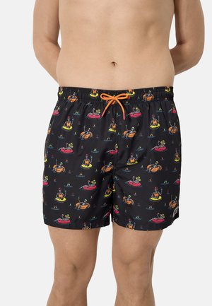 Pantalones cortos de baño negros con patrones de flotadores inflables de colores y esqueletos, con cintura ajustable con cordón naranja, usados por una persona de pie.