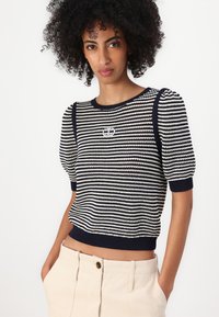 Maglione a righe blu navy e bianche in maglia, con maniche a palloncino corte e scollatura rotonda, caratterizzato da un dettaglio del logo argentato sul petto.