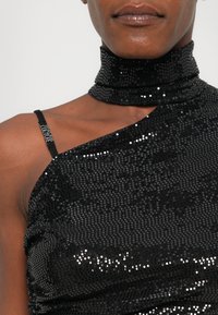 Black sequined top with a high collar, asymmetrical design, and thin strap. Features a smooth texture and a reflective surface.