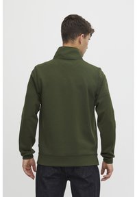 Grön sweatshirt med hög krage, långärmad och en åtsittande design. Tillverkad av mjukt material, med en ren finish och utan synliga logotyper.