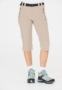 Beige capri-bukser med et sort b�ælte, der har front-zip lommer. Båret med grå vandresko med turkise snørebånd og hvide sokker.