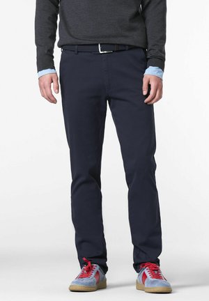 Marineblaue Chinos aus Baumwolle, mit slim fit, Gürtelschlaufen und einem strukturierten Gürtel. Kombiniert mit mehrfarbigen Sneakers.