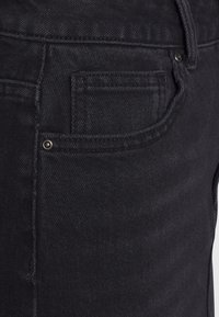 Svarta denimjeans med en klassisk femfickdesign, subtil textur och metalldetaljer vid fickorna för en extra touch.