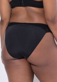 Černé vysoké spodní prádlo s hladkým tělem a krajkovým lemem v pase. Obsahuje bezešvý design pro pohodlí a správné padnutí.
