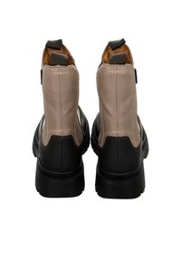 Black and beige leather ankle boots with a textured finish, elastic side panels, and sturdy rubber soles for traction.