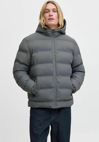 Szara puchowa kurtka z kapturem, posiadająca pikowane sekcje, zamek błyskawiczny z przodu i boczne kieszenie. Gładka tekstura i minimalistyczny design.