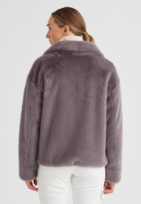 Faux-Fur-Jacke in sanften Grau mit lässiger Passform, großem Kragen und langen Ärmeln. Die Textur ist plüschig und gemütlich, ideal für kaltes Wetter.