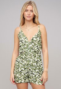 Roheline lillemusteriga jumpsuit, millel on sügav V-kaelus ja õhukesed rihmad. Omab elastset vööd ja lõõgastavat istuvust, segades valgeid ja musti lillemustreid.