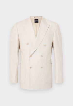 Beige dubbelzijdig blazer gemaakt van textuurstof. Bevat twee opgestikte zakken en een notch-lapel. Merkje zichtbaar aan de binnenkant van de kraag.