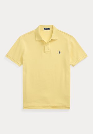 Polo jaune clair à manches courtes avec col, patte à deux boutons et petit logo brodé bleu foncé sur la poitrine.