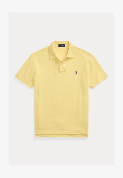 Svijetložuta polo majica kratkih rukava s ovratnikom, preklopnikom na dva gumba i malim tamnoplavo izvezenim logotipom na prsima.