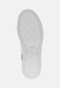 Suola di sneaker bianca con logo in rilievo. Il motivo testurizzato presenta piccoli disegni interconnessi. Forma arrotondata con bordi laterali lisci.