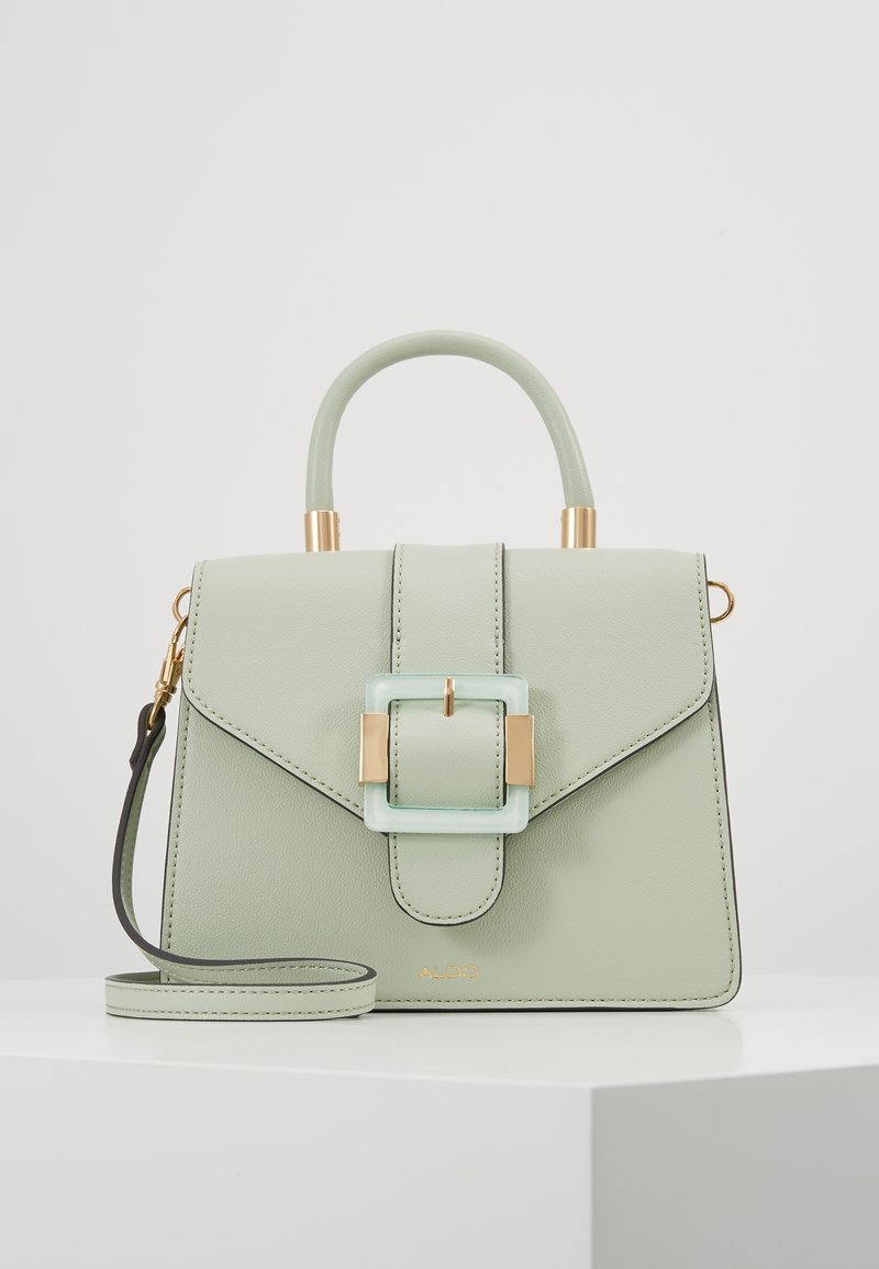 Tyrkysová kožená kabelka se strukturovaným designem, zlatými akcenty a průhlednou sponou. Má horní držadlo a odnímatelný ramenní popruh.