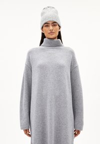 Grijze gebreide coltrui jurk gemaakt van zachte stof, met lange mouwen en een aansluitende kraag, gecombineerd met een bijpassende geribde beanie.