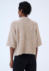 Beige fuzzy knit sweater with short sleeves and a cropped design, featuring a rounded neckline and a slightly textured finish.