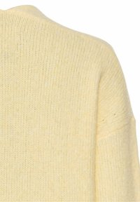 Tissu de pull tricoté doux, jaune pâle, montrant l'épaule et le haut de la manche avec une texture côtelée et un motif de maille lâche.