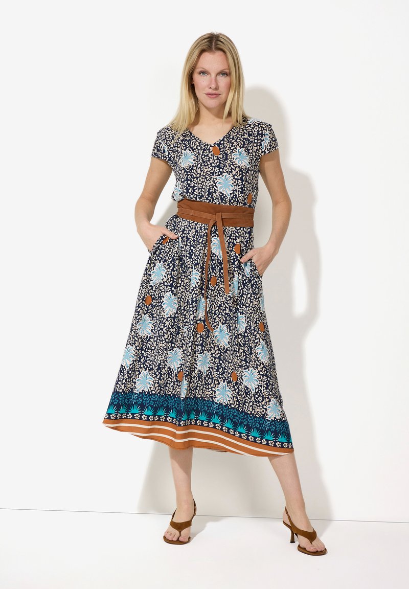 Blumenkleid in Midi-Länge mit kurzen Ärmeln; navy Hintergrund, türkisfarbene und orange Muster, tailliert mit einem braunen Gürtel und Taschen.