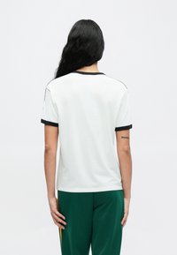 White short-sleeve t-shirt with black trim at the collar and sleeves. Features a plain back without visible graphics or logos.