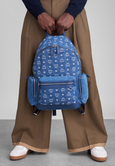 Μπλε τζιν σακίδιο με μοτίβο logo σε όλη την επιφάνεια, δύο πλαϊνές τσέπες και χερούλια στην κορυφή. Κλείσιμο με φερμουάρ και δομημένο σχήμα.
