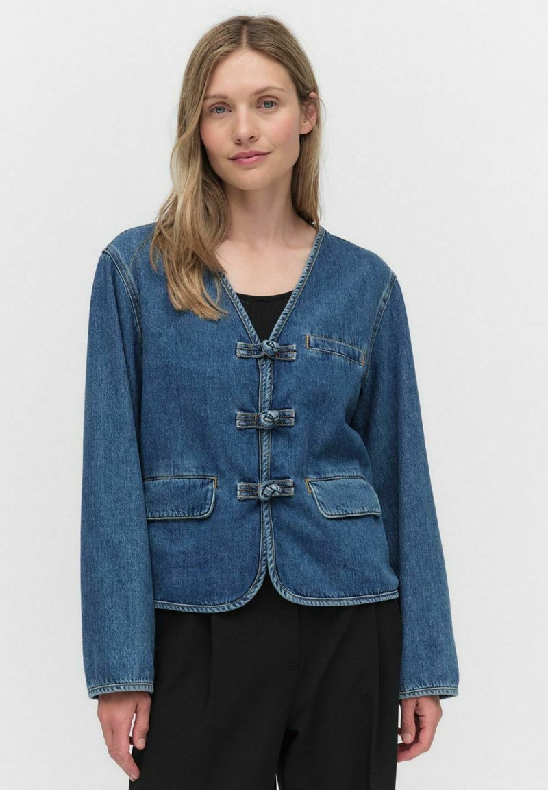 Veste en denim bleu foncé avec un col en V, des manches longues et quatre fermetures à boutons en nœud. Elle possède deux poches avant et des coutures contrastées.