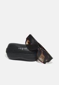 Akiniai nuo saulės su vėžlio kiauto raštu, stačiakampio formos, supakuoti juodame kietame dėkle su užtrauktuku ir baltu "vogue" tekstu.