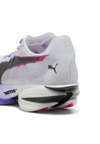 Baskets de course blanches avec un upper en maille texturée, des accents noirs et roses, et un logo bien en vue. Dotées d'une semelle amortissante avec un design multicolore.