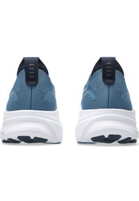 Sneaker in tessuto blu con suola bianca liscia, tallone rinforzato e accenti blu scuro a contrasto. Design semplicistico con branding minimale.