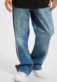Lyseblå denimjeans med en avslappet passform, med subtil fading og rett ben-design. Kombinert med hvite sneakers.