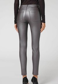 Jean skinny gris métallique avec une texture lisse, deux poches arrière, des détails de couture subtils et une taille mi-haute.
