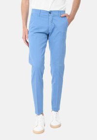 Chinos azzurro chiaro in cotone, con vestibilità slim, tasche frontali e chiusura con bottone, abbinati a sneakers bianche.