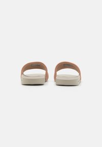 Infradito rosa chiaro con tomaia in tessuto morbido e suola in gomma beige. Il design minimalista presenta un retro e una punta aperti.