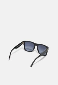 Sorte plastikk sunglasses med mørk grå gradientlinser, firkantet form og slanke sider. Merkbar gullhardware-aksent på stangkanten.