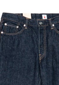 Donkerblauwe denim jeans met contrasterende oranje stiksels, vijf zakken, zilveren hardware en een etiket op de tailleband. Zachte, gestructureerde stof.