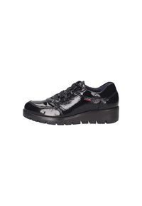 Zapatillas de piel sintética negra con punta redonda, diseño de cordones y suela acolchada. Presenta una marca sutil en el lateral.