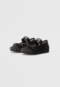 Sorte balletflats med et mykt stoff-overdel, med en bue detalj, kryssende stropper og en flat gummisåle. Minimalistisk design og finish.