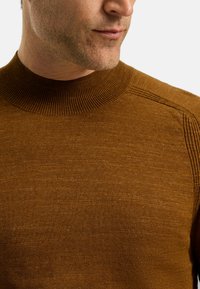 Brauner Strickpullover mit einem hohen, gerippten Kragen. Besitzt eine weiche Textur und subtile Farbvariationen im gesamten Stoff.