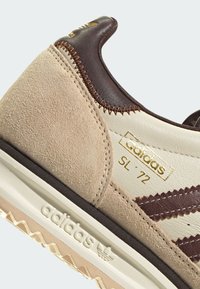 Teniska Adidas SL '72 s béžovou semišovou a koženou podešví, hnědými doplňky, zlatým logem a texturovanou gumovou podrážkou se vzorem cik-cak.