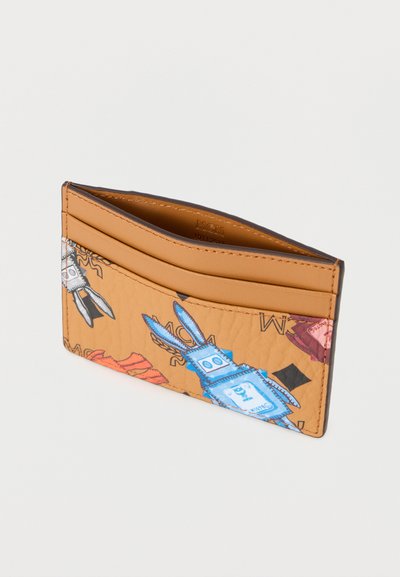 Δερμάτινη θήκη καρτών σε ταμπά χρώμα με γραφικό σχέδιο που απεικονίζει μπλε ψαλίδια και κόκκινες λεπτομέρειες. Περιλαμβάνει πολλαπλές θήκες για κάρτες για καλύτερη οργάνωση.