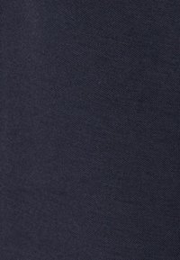 Tissu bleu marine foncé avec un motif tricoté finement texturé, montrant des détails en gros plan de la surface du matériau.