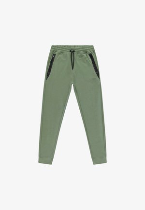 Groene joggingsbroek met een tailleband met koord, voorzien van zwarte zakken met rits aan beide zijden en taps toelopende boorden bij de enkels. Glad textuur van de stof.