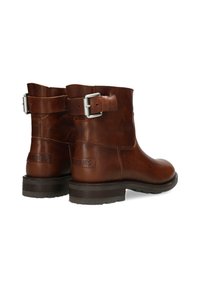 Brown leather ankle boots with a side buckle, rounded toe, and a low stacked heel. Features embossed branding on the back.