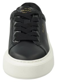 Mustad musta nahast tossud, millel on ümmargune varvas, lamedad lipsud, pehme kaelus ja valgest tekstuurses kummist tallast koos minimaalsete brändingu elementidega.