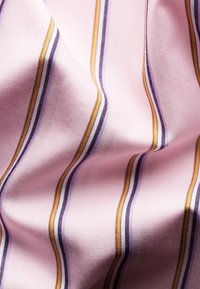 Tissu lisse avec des rayures verticales jaunes, noires et violettes sur un fond rose pâle, montrant des plis et de la texture.
