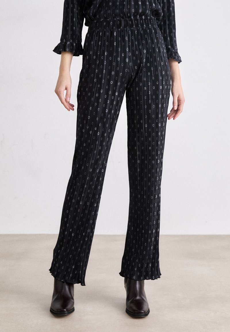Pantalons noirs à rayures avec une coupe décontractée. Dotés d'une taille élastique, d'ourlets effilochés et de détails argentés subtils. Texture de tissu lisse.