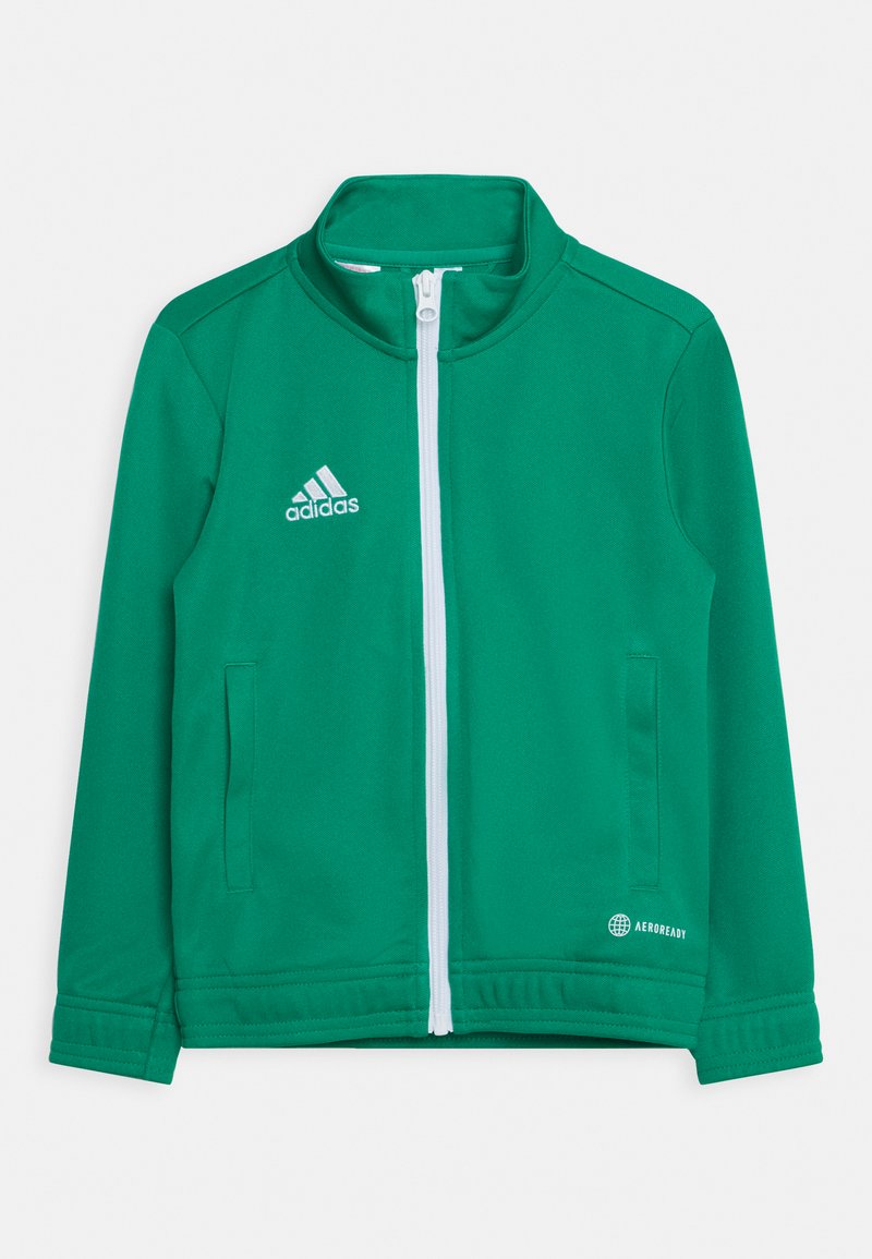 Veste de sport verte en tissu lisse, dotée d'une fermeture éclair blanche, d'un logo contrastant et de deux poches latérales.