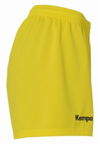 Pantalones cortos deportivos amarillos con cinturilla elástica, tejido suave y logo negro "Kempa" en la parte inferior derecha.