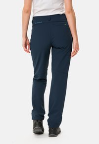 Pantalons bleu marine en tissu extensible, avec une coupe slim, une taille plate, une poche arrière et des jambes fuselées avec des coutures renforcées.