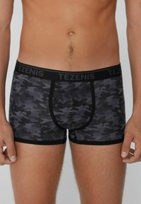 Černé a šedé maskáčové boxerky s černým pasem označeným "TEZENIS"; vyrobené z měkké tkaniny, mají přiléhavý střih a ploché švy.